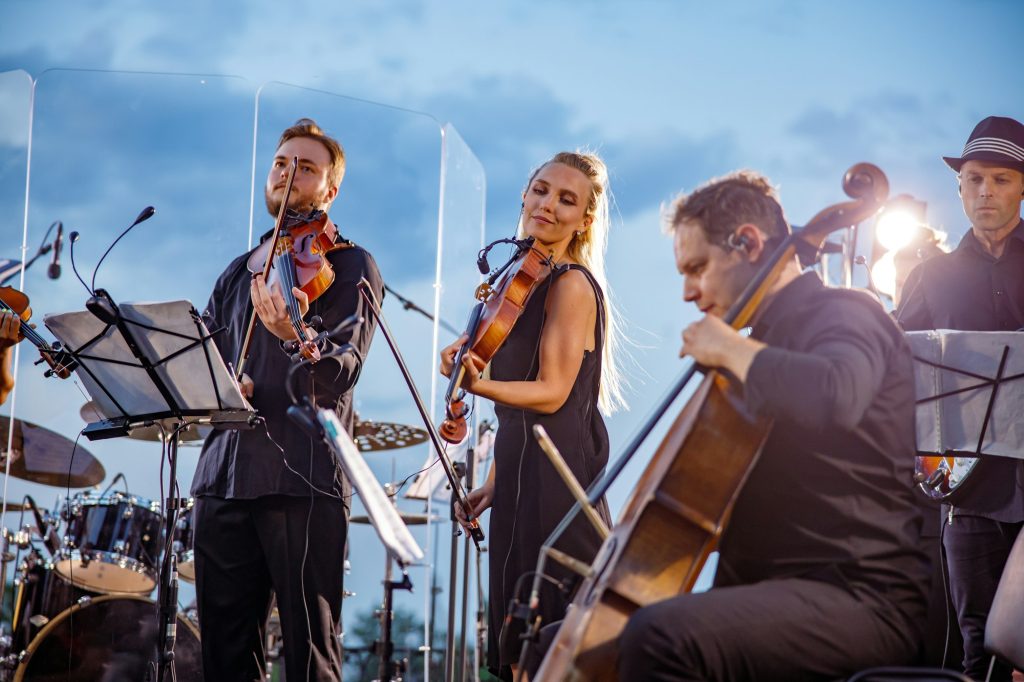 Musical ensemble performing orchestra concert against blue sky